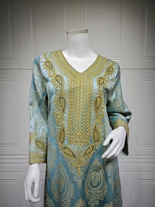 Détail de la broderie paisley dorée sur le col en V de la robe caftan bleu clair