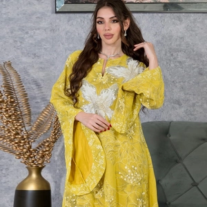 Close-up of white floral embroidery and sequins on mustard yellow maxi dress