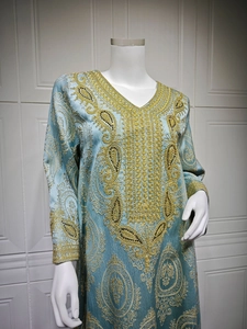 Détail de broderies cachemire dorées et perles noires sur le caftan bleu clair