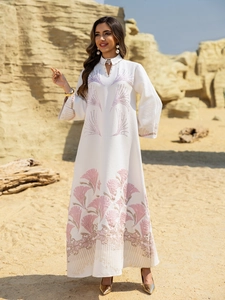 Close-up of white jacquard dress featuring floral embroidery and rhinestone neckline