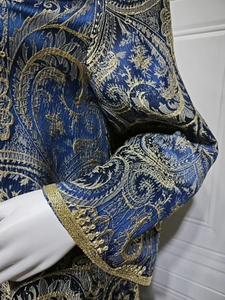 Detailed view of dark blue evening kaftan with gold paisley jacquard and embroidered cuffs