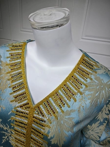 Close-up of V-neckline with golden bead embroidery and leaf pattern jacquard detail