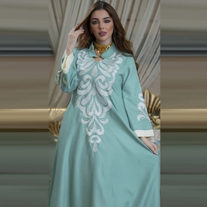 Close-up of white floral embroidery and contrast cuffs on mint green linen kaftan dress