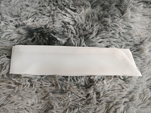 Detail of a long white satin ribbon texture laid on a soft grey faux fur surface
