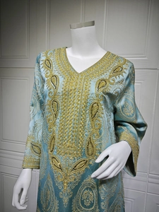 Détail de broderie dorée et motifs cachemire sur le tissu de robe Kaftan bleu clair