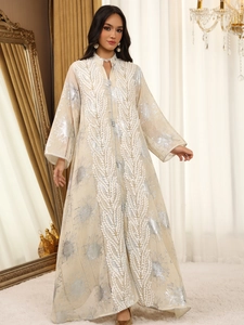Detailansicht der Silberblatt-Stickerei und des Posamentenverschlusses am beigen Abaya-Kleid