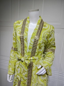 Dettaglio del maxi vestito caftano verde lime con ricami bianchi e paillettes dorate