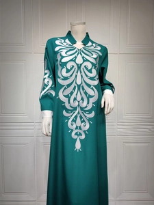 Detail of white embroidery patterns on dark green long-sleeved ethnic maxi dress