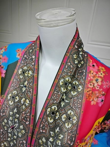 Detail of bohemian printed cardigan with vibrant floral patterns and sparkling sequins