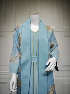 Close-up of light blue abaya set with delicate gold floral embroidery on textured fabric
