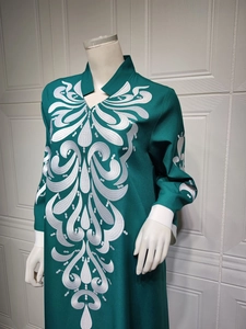 Close-up detail of white embroidery on a dark green long-sleeved kaftan dress