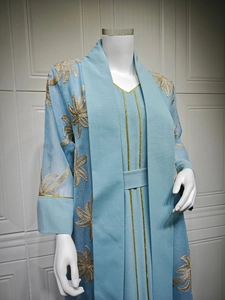 Detail of golden floral embroidery on semi-transparent sleeves of light blue Abaya