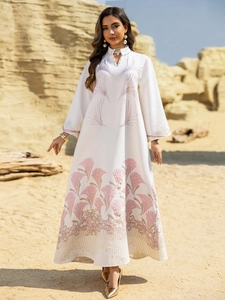 Detail of white Abaya with palm leaf print, pearl neckline, and embroidered hemline