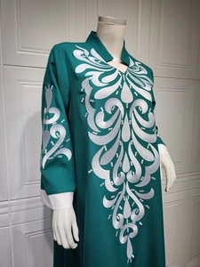 Close-up of white floral embroidery on dark green kaftan dress with high neck