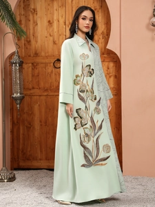 Detail of floral sequin embroidery and marble-textured pleated fabric on mint green dress