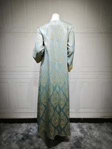 Détail de la robe caftan bleu clair avec motifs jacquard dorés et texture satinée