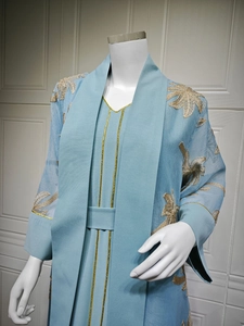 Close-up of golden palm leaf embroidery on light blue embroidered chiffon abaya