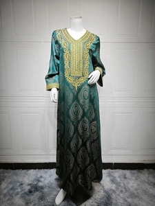 Détail d'une robe caftan vert foncé luxueuse avec broderies dorées et décolleté en V profond