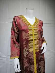 Close-up of wine red kaftan featuring golden maple leaf jacquard and intricate yellow embroidery