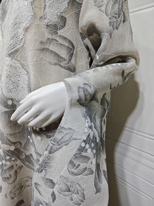 Close-up of floral embroidery and shiny sequins on a beige long sleeve maxi dress