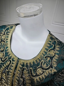 Detail of dark green evening dress featuring intricate gold embroidery and black beadwork