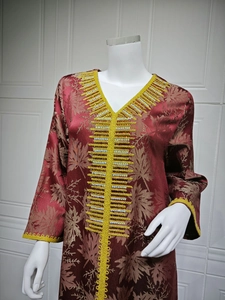 Detail of burgundy kaftan featuring leaf jacquard and yellow bead embroidery on V-neckline