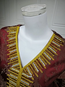 Detail of V-neckline with gold sequins and beads on dark red floral jacquard dress