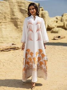 Detail of white long sleeve kaftan dress with golden embroidery and ethnic pattern trim