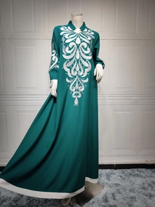 Close-up of white vine embroidery on a dark green ethnic long dress with stand collar