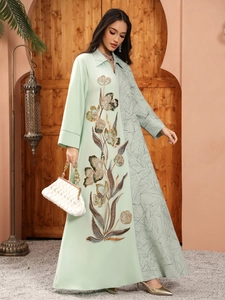 Detail of floral sequin embroidery and leaf pattern on a light green Abaya dress