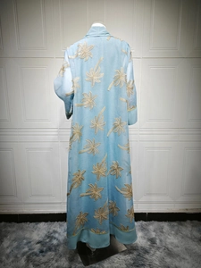Detail of light blue abaya cardigan with gold palm tree embroidery and banded hem