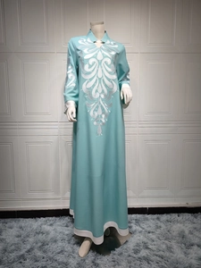 Close-up of white silk embroidery on tiffany blue long sleeve kaftan dress neck
