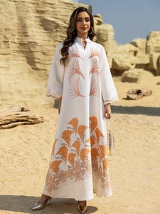 Detail of white jacquard kaftan with orange embroidery and rhinestone accents