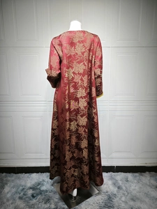 Detail view of the back of a deep red kaftan dress with gold maple leaf jacquard pattern
