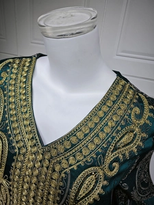 Détail de broderies dorées et motifs paisley sur une robe caftan en velours vert foncé