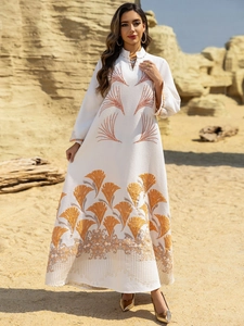 Detail of white maxi dress featuring gold leaf embroidery and textured fabric in a desert set