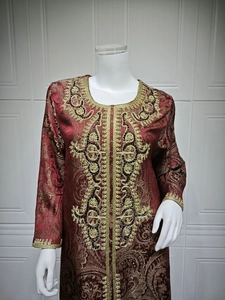 Close-up of golden embroidery and black beadwork on luxury burgundy kaftan evening dress