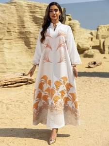 Detail of white long sleeve Abaya dress featuring orange fan-shaped embroidery in desert