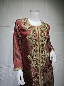 Detailed close-up of golden embroidery and beadwork on a dark red kaftan dress