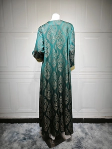 Vue détaillée du caftan vert foncé avec jacquard floral doré et drapé dans le dos