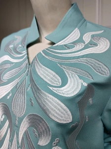 Detailed view of white embroidery on a light blue traditional linen ethnic dress