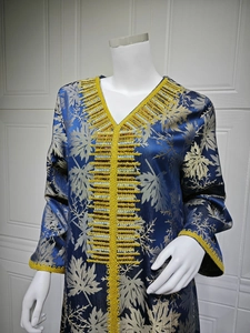 Detailed close-up of golden embroidery and blue beadwork on a navy blue kaftan collar