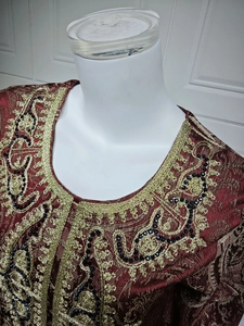 Detail of burgundy jacquard kaftan with ornate gold embroidery and black beadwork