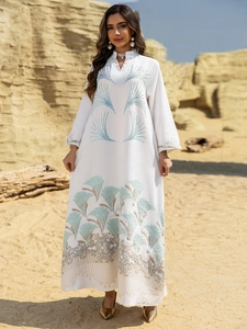 Detailed teal fan pattern embroidery on white long sleeve abaya dress in desert setting