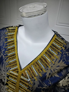 Detail of V-neckline with gold embroidery and orange crystal rhinestones on navy dress