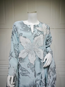 Detail of light blue dress featuring white sequin flower embroidery and floral patterns