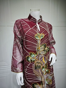 Dettaglio di abito in rete bordeaux stile etnico con ricamo di paillettes floreali