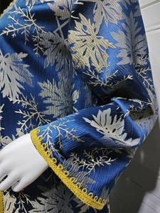 Close-up of royal blue jacquard dress sleeve with gold leaf embroidery and yellow lace