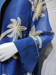 Detail of navy blue cardigan dress featuring intricate beige palm leaf embroidery