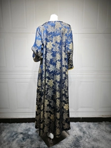 Detailed close-up of dark blue kaftan dress with golden leaf jacquard and sleeve trim